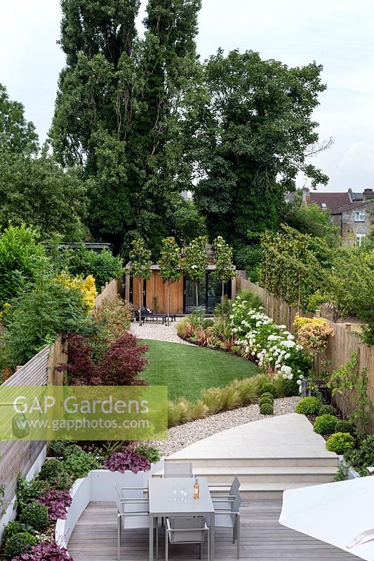 High view of contemporary garden with wood deck patio and artificial lawn. 