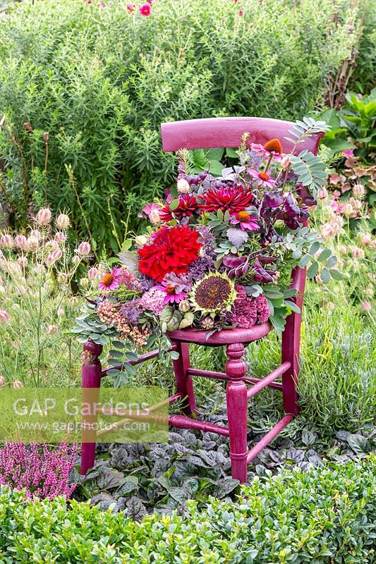 Vintage dark red wooden chair with floral arrangement placed in border. 