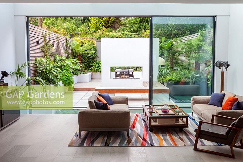 Modern London garden planted with lush foliage, view from house to garden