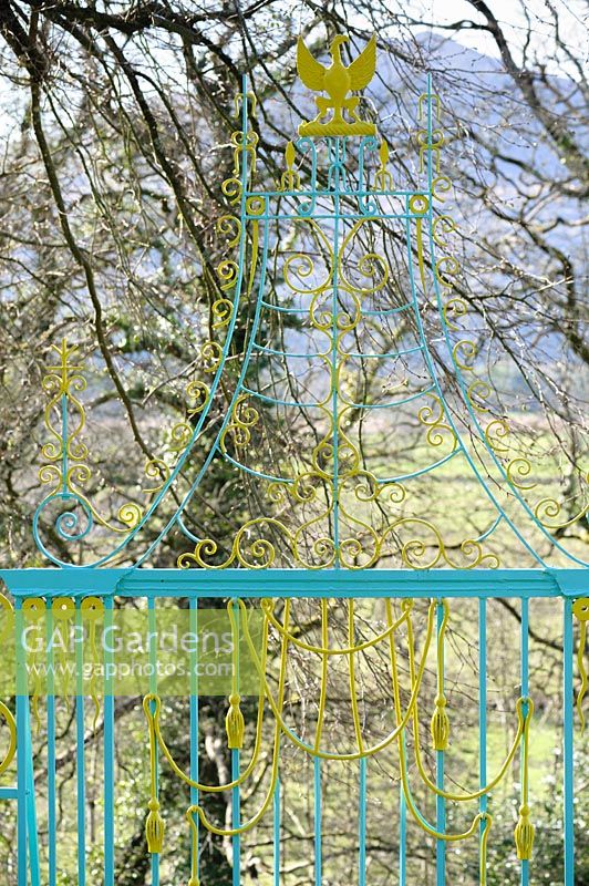 Decorative metalwork around the garden is painted in bright yellow and turquoise. Plas Brondanw, Penrhyndeudraeth, Gwynedd, Wales