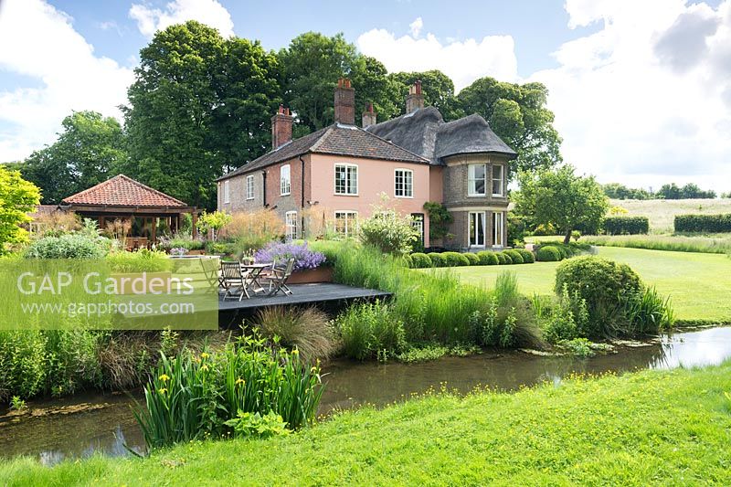 View accross the river to the house and garden, Norfolk, UK. 