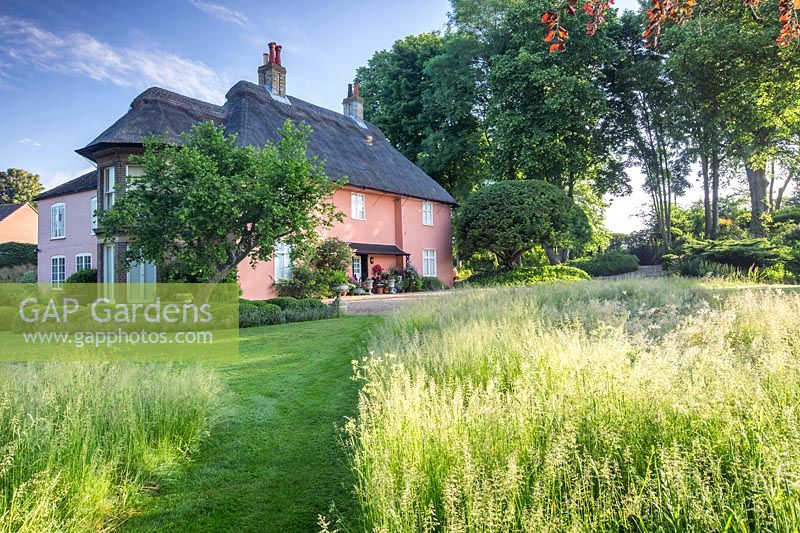 View accross the wild meadow to the house at David and Loretta Harrison's Garden, Norfolk, UK. 