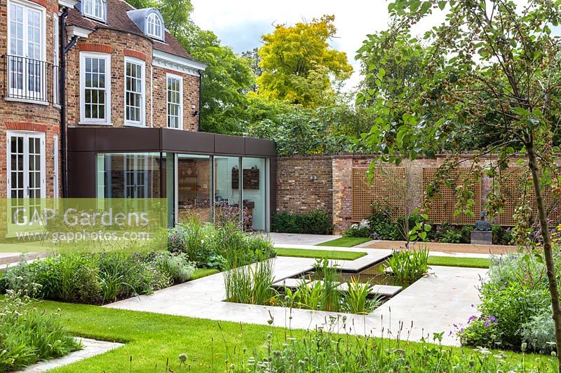 Modern pond with stepping stones. Garden design by Peter Reader Landscapes.