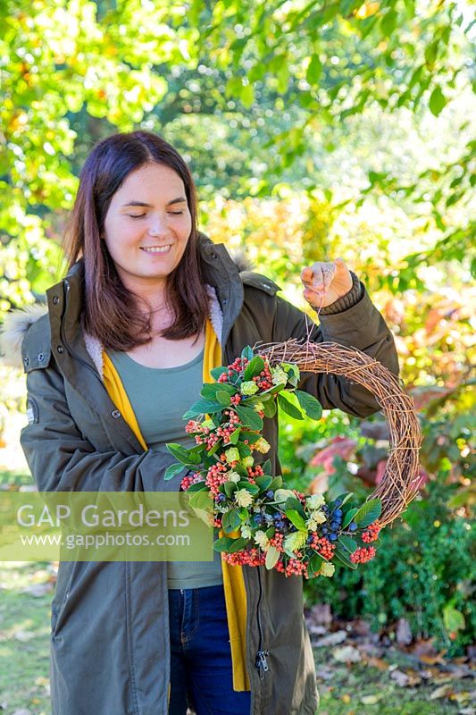 Holding autumnal deocrative wreath, with hop flowers, Cotoneaster and sloes.