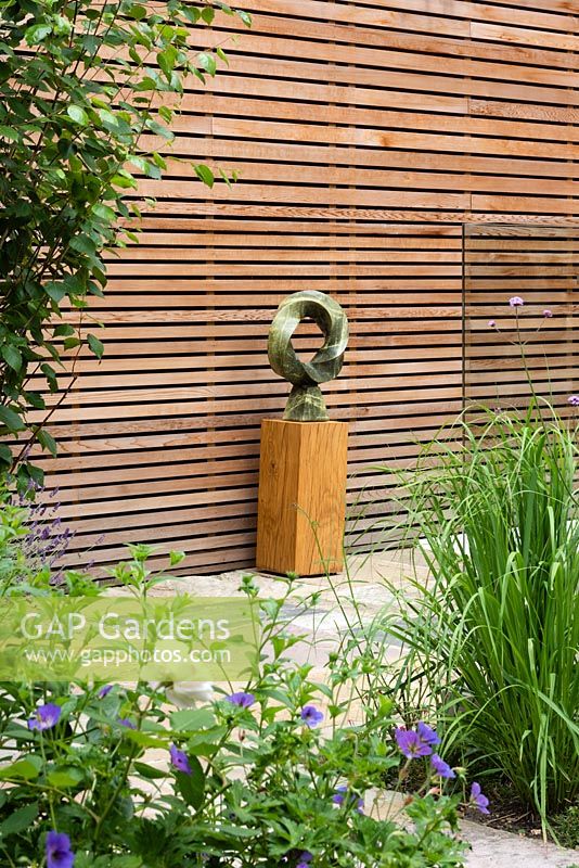 View of modern sculpture in front of cedar cladded wall. 
