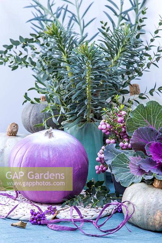 Purple, white and blue autumnal arrangement, with pumpkins, ornamental cabbages, Pernettya and cut foliage.