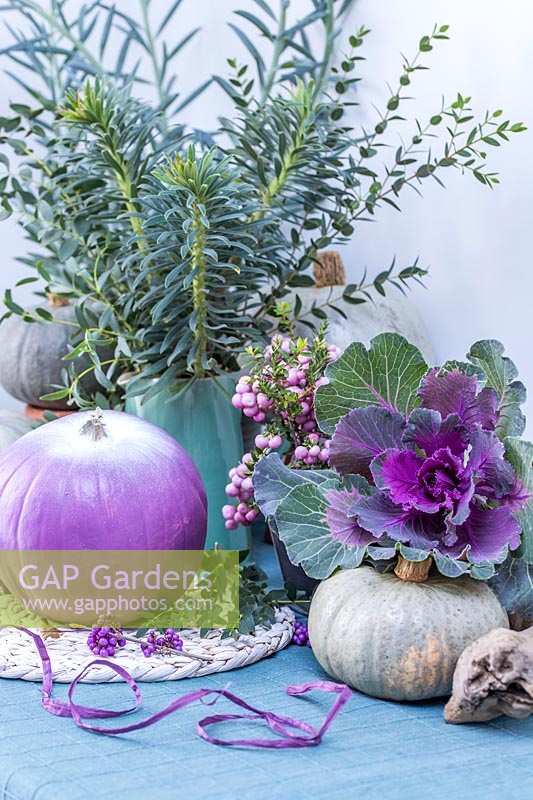 Purple, white and blue autumnal arrangement, with pumpkins, ornamental cabbages and Pernettya.