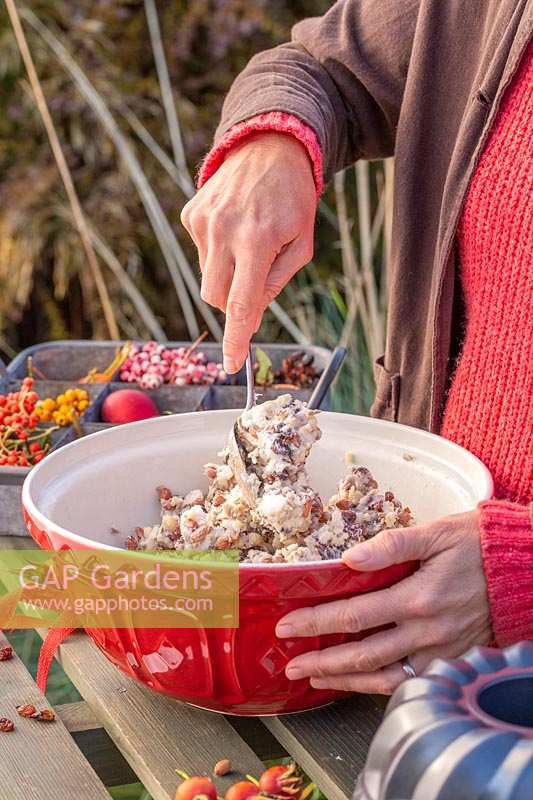 Woman mixing lard, nuts and raisins together to make bird feed cake mixture.