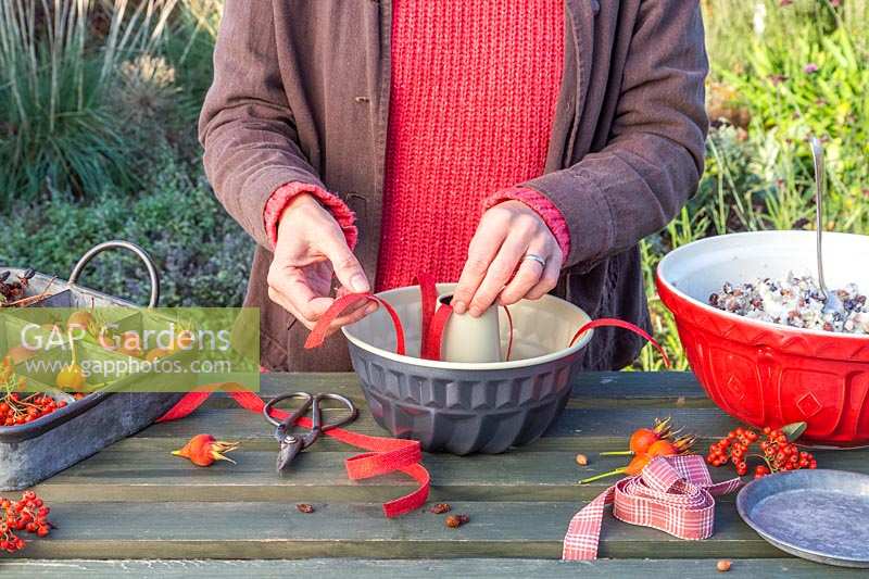 Woman adding lengths of ribbon to bundt cake tin prior to adding bird feed mix, to help remove cake from tin if it gets stuck.