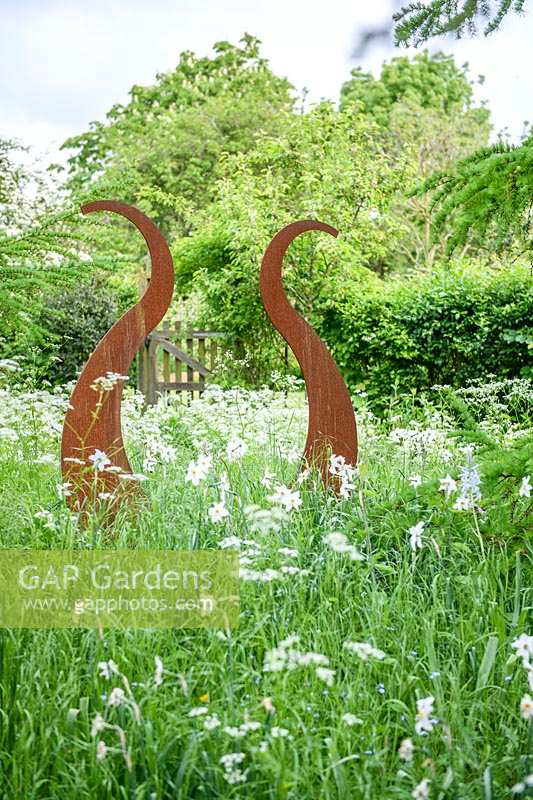 Rusty steel Lyre sculpture in a wild garden. 