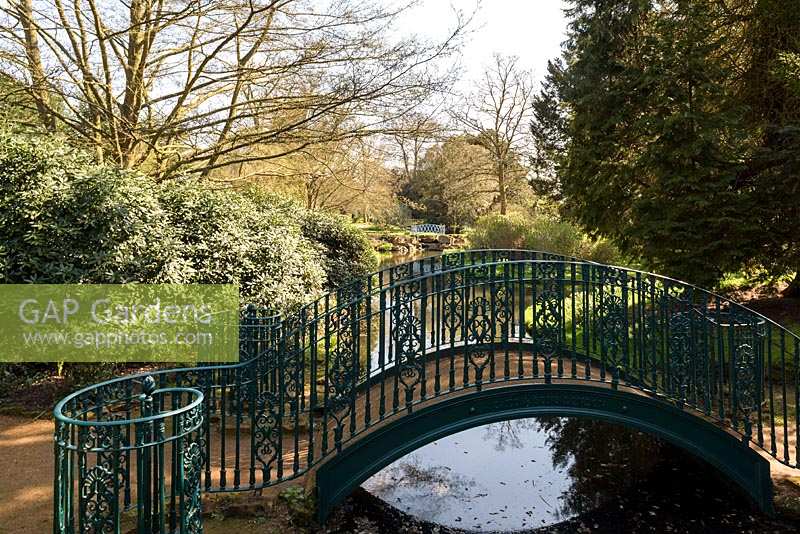 Arched foot-bridge with painted metal railing over water
