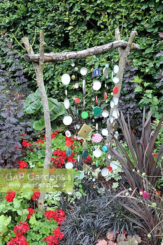 Home made decorative structure with glass jar lids in a flowerbed