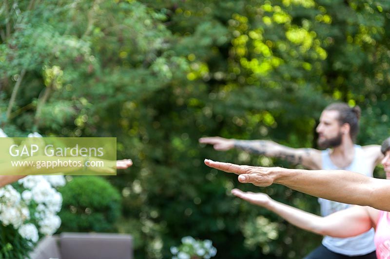 People practicing yoga in garden.