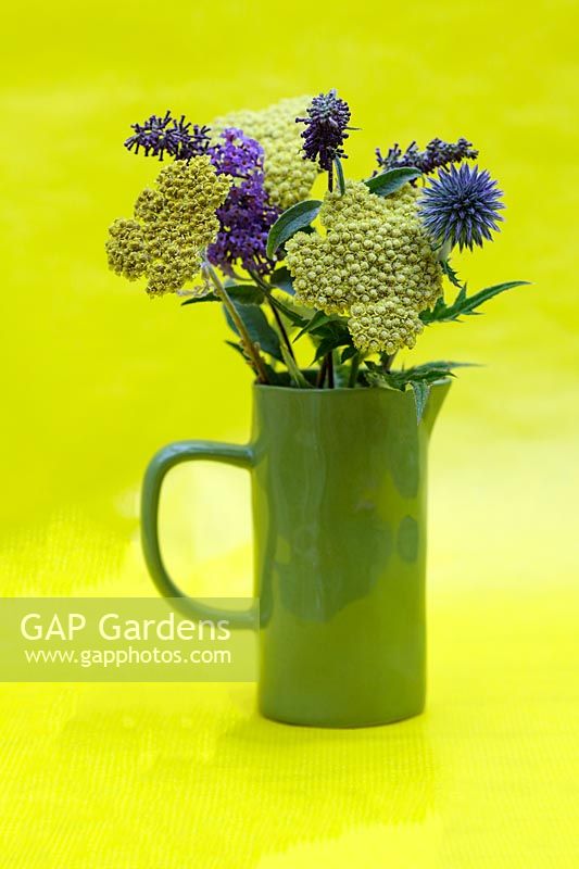 Green jug of summer flowers including Achillea 'Moonshine' - Yarrow,  Buddleia davidii 'Nanho Blue' - Butterfly Bush and Echinops ritro - Globe Thistle. 