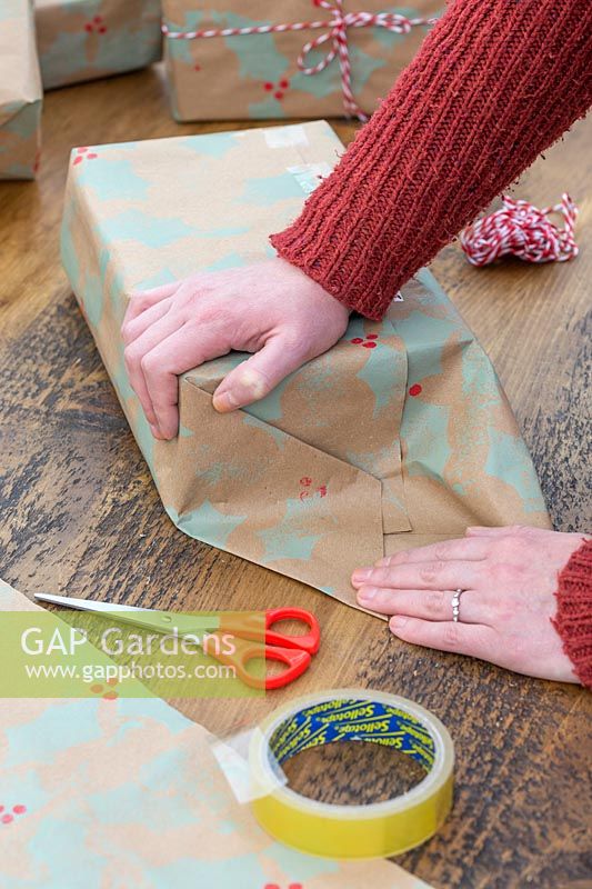 Woman wrapping gift with hand stamped craft wrapping paper.