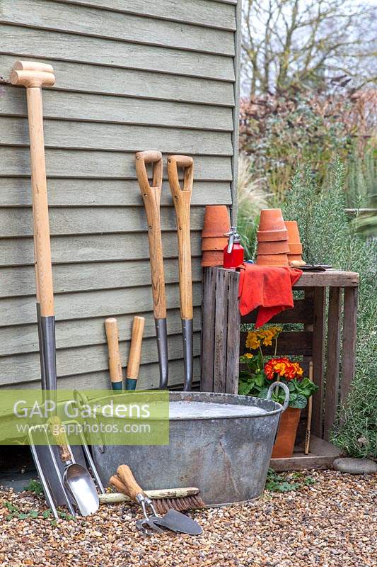 Washing tools: Clean garden tools leaning against side of shed to dry next to metal tub of soapy water.