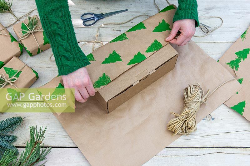 Woman wrapping gift with hand stamped christmas wrapping paper.