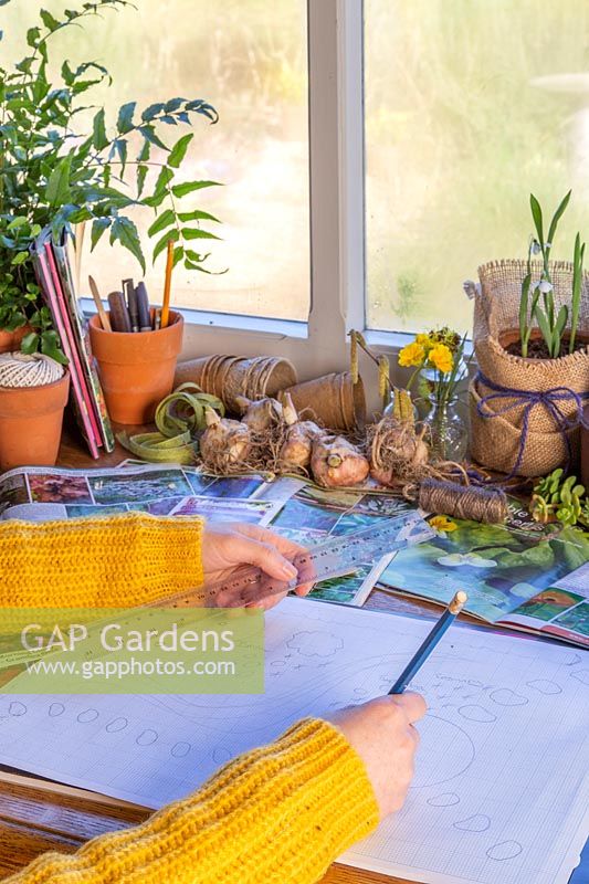 Woman drawing out garden plan on graph paper.