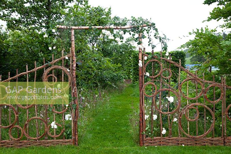 Hazel and willow decorative fence in pattern of circles and an arch in the show garden Belmond Enchanted Gardens 