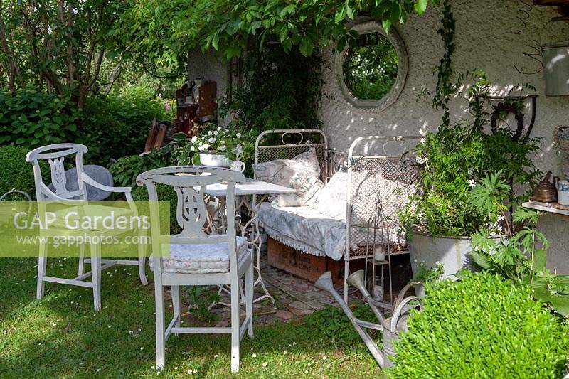 Relaxing area in shade, an old decorative bed, antique chairs and planted pots