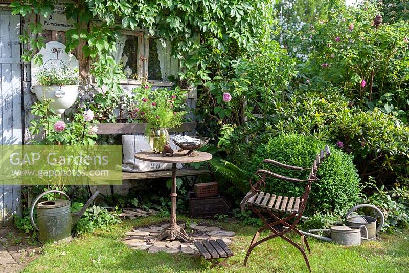 Seating area made from vintage collectables in cottage garden setting
