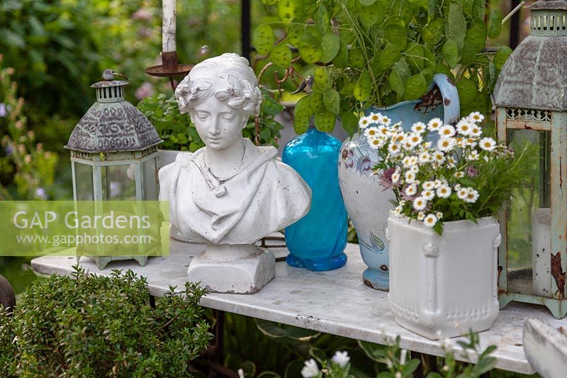 Vintage decorations with a bust of a woman, lanterns, potted plant and jug of honesty 