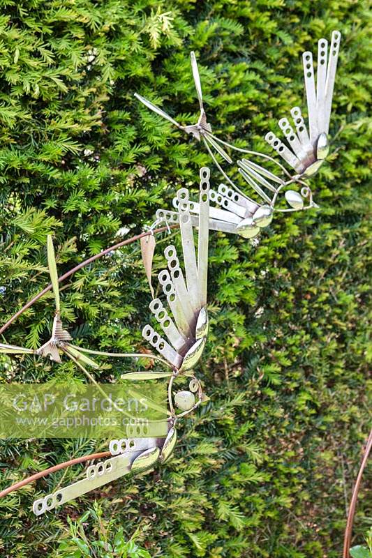 Birds and Bees - artwork made of steel cutlery - shown against a hedge
