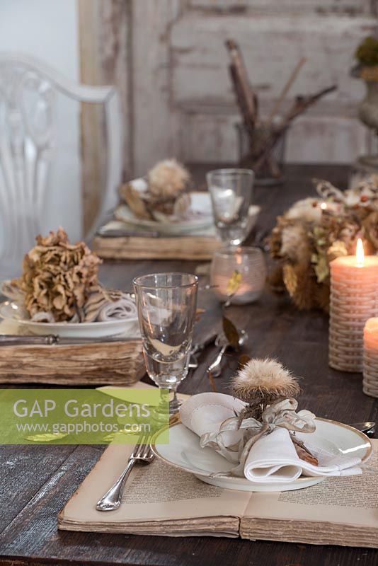 Dried Hydrangea and vintage book table and place setting with glasses and lit candles