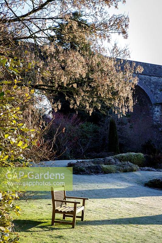 Wooden bench sits on frosted lawn at Kilver Court, Somerset, UK. Designed by Roger Saul of Mulberry.