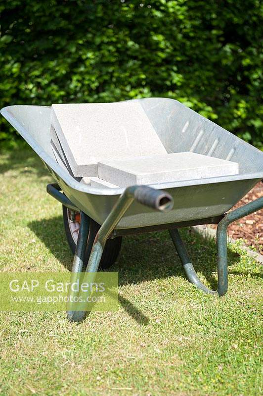Wheelbarrow with paving slabs for foundation for children's playhouse. 