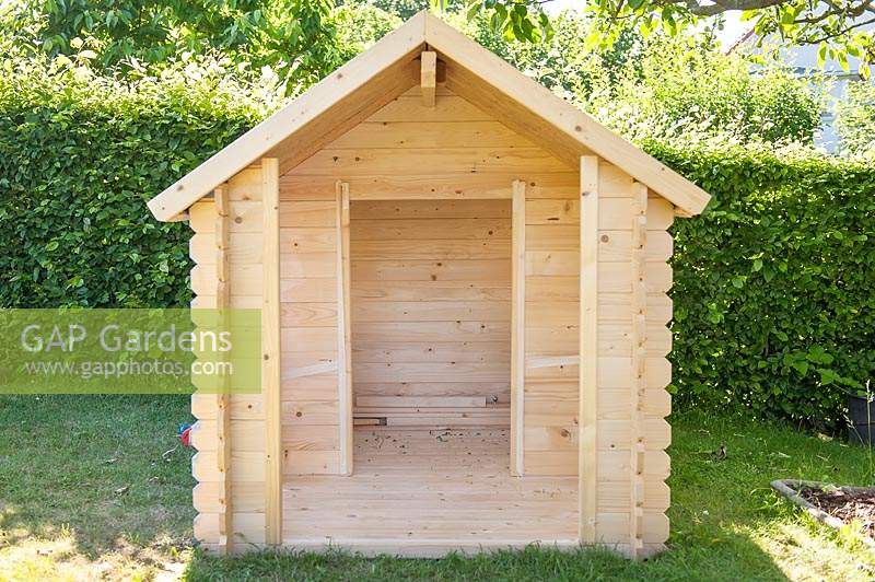 Front side of a newly built wooden playhouse in garden. 