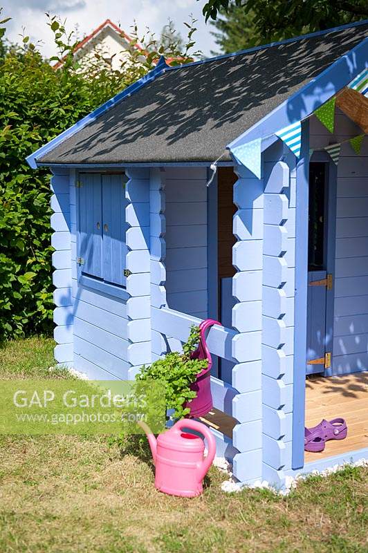 Blue painted children's playhouse in garden. 