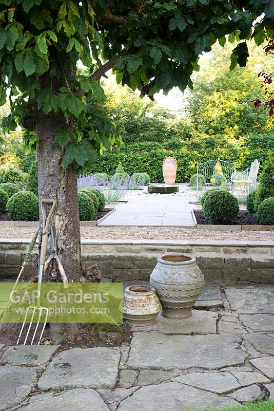 Formal garden with seating, central millstone water feature and topiary
