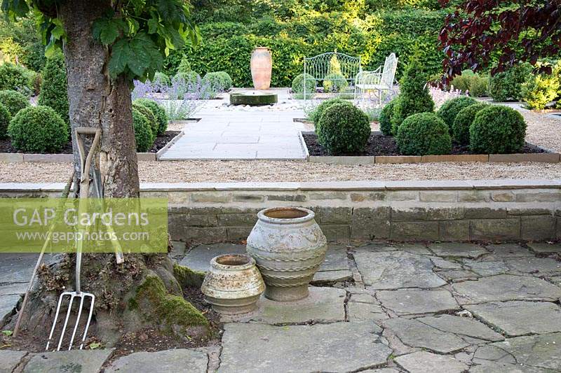 Formal garden with seating, central millstone water feature and topiary 