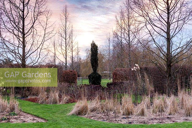 View to Topiarised Taxus baccata 'Fastigiata' based on 'Broken Obelisk' by Barnett Newman. The Art Gardens, Stevington Manor Gardens, Stevington, UK. 