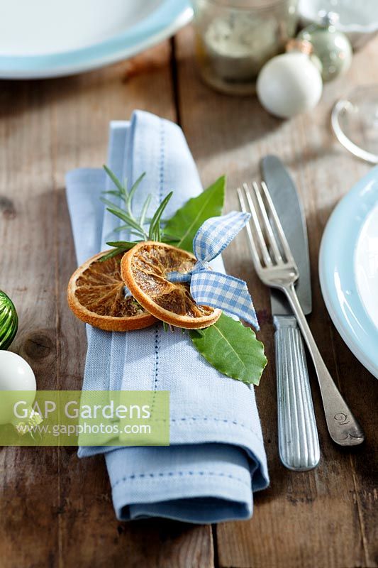 Create your own napkin rings using natural materials - dried orange slices, bay leaves and rosemary tied together with blue gingham ribbon