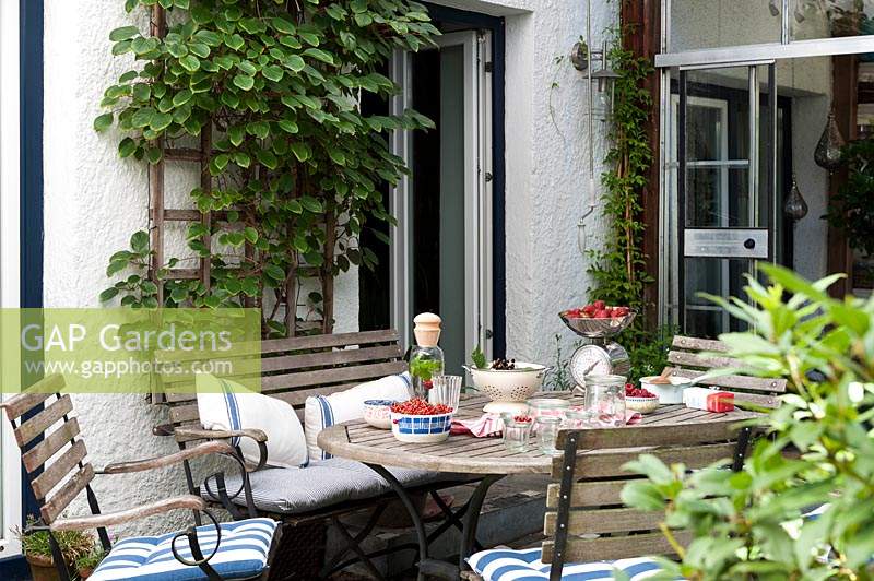 Summer terrace with seating  and table filled with harvested fruit for preserving  