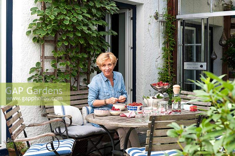 Woman sitting at garden table sorting through harvested soft fruit 