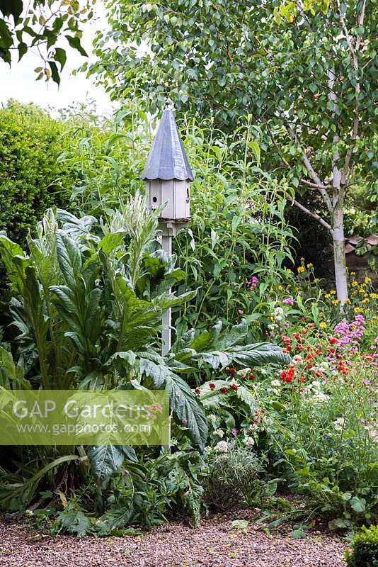 A dovecote style nesting box creates a pretty focal point in the gravel garden. 