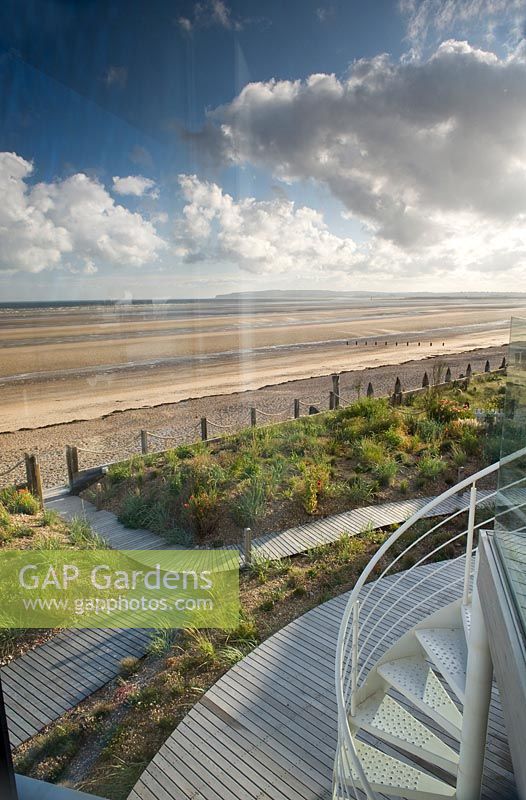 View down to gravel-mulched borders by decked pathways, with view to beach. 