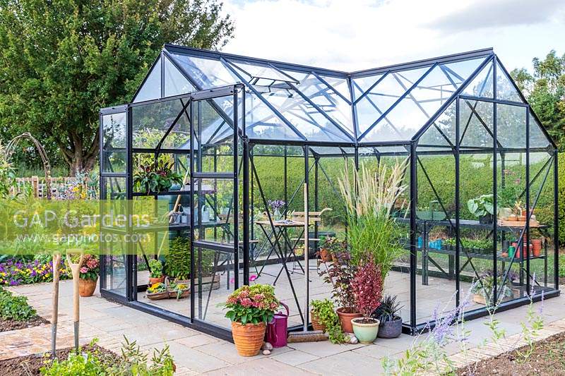 Large greenhouse with double sliding doors in vegetable garden.