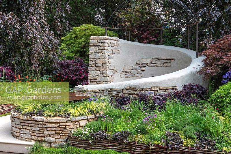 The Kingston Maurward Garden. A romantic curving seating area in Purbeck stone, enclosed in purple beeches, acers and herbaceous planting. Sponsors: Miles Brown, Kingston Maurward College, Goulds Garden Centre, Wilks Landscaping, Holme for Gardens, The Green Gardener.