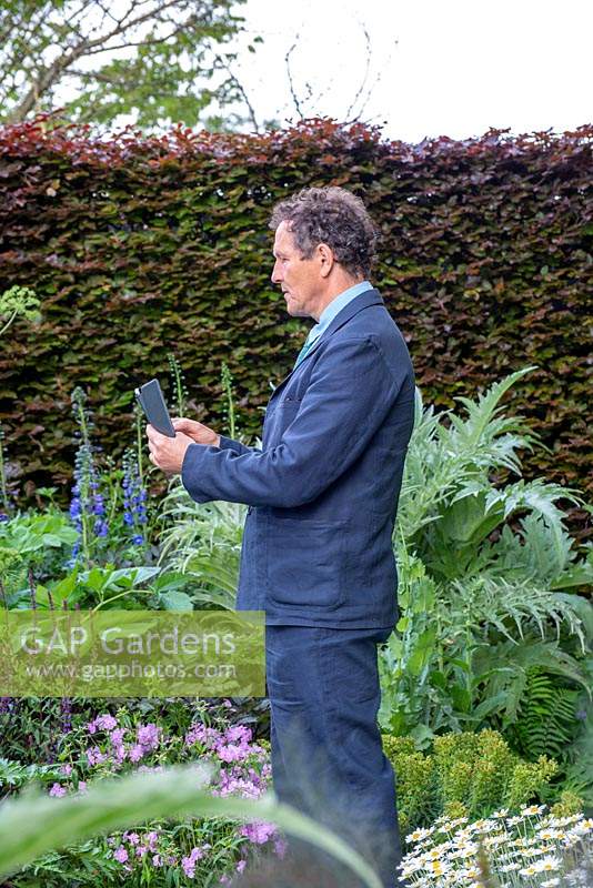Monty Don taking a picture on his smartphone whilst filming on The Morgan Stanley Garden, RHS Chelsea Flower Show 2019.