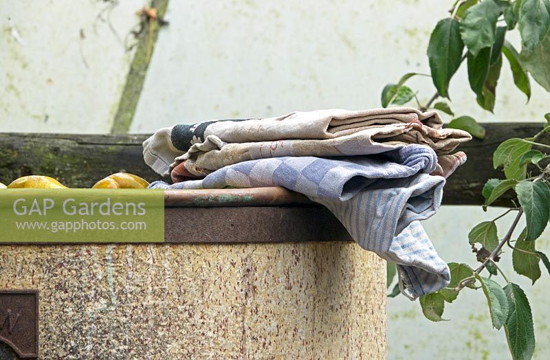 Old towels covering fruit in a copper boiler while cooking.