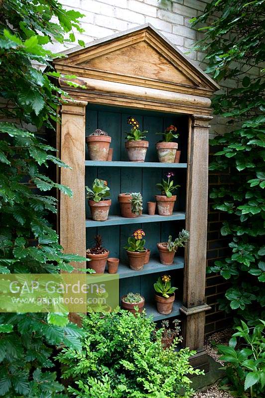 Wooden set of shelves displaying potted plants. 