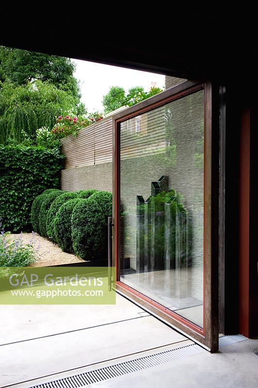 View through open garden sliding door to contemporary garden. 