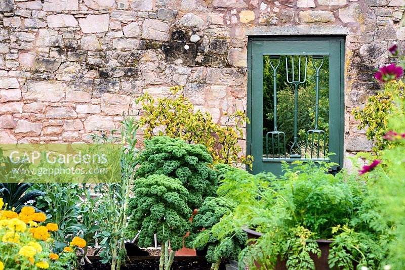 A door into the Walled Garden incorporating old hand forks at Broadwoodside, Gifford, East Lothian, Scotland