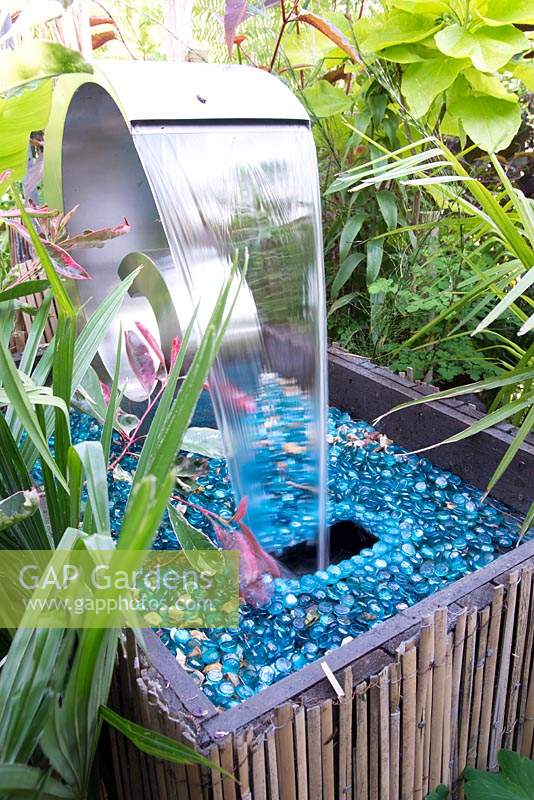 Water feature in a small town garden with tropical foliage plants