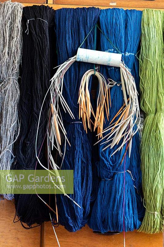 Alison Ellen Hand Knits studio - Knitting needles hanging with loose hanks of wools which were dip dyed using acid dyes to give a range of natural colours