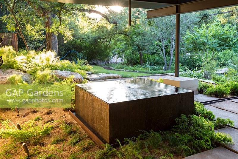 Square copper water feature near gravel bed with woodland beyond